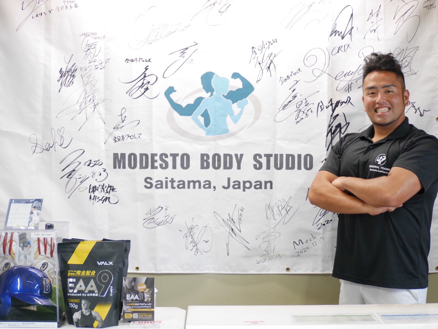 代表トレーナー 成田武尊(選手のサイン壁の前で)